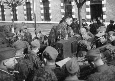 Waffen-SS members listen to a radio announcement