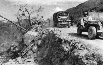 French forces advance through the mountains pass a knocked out Marder III H.