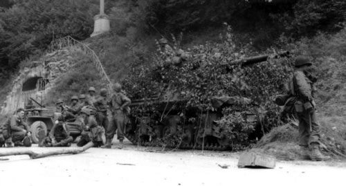 Camouflaged Sherman halts by a road